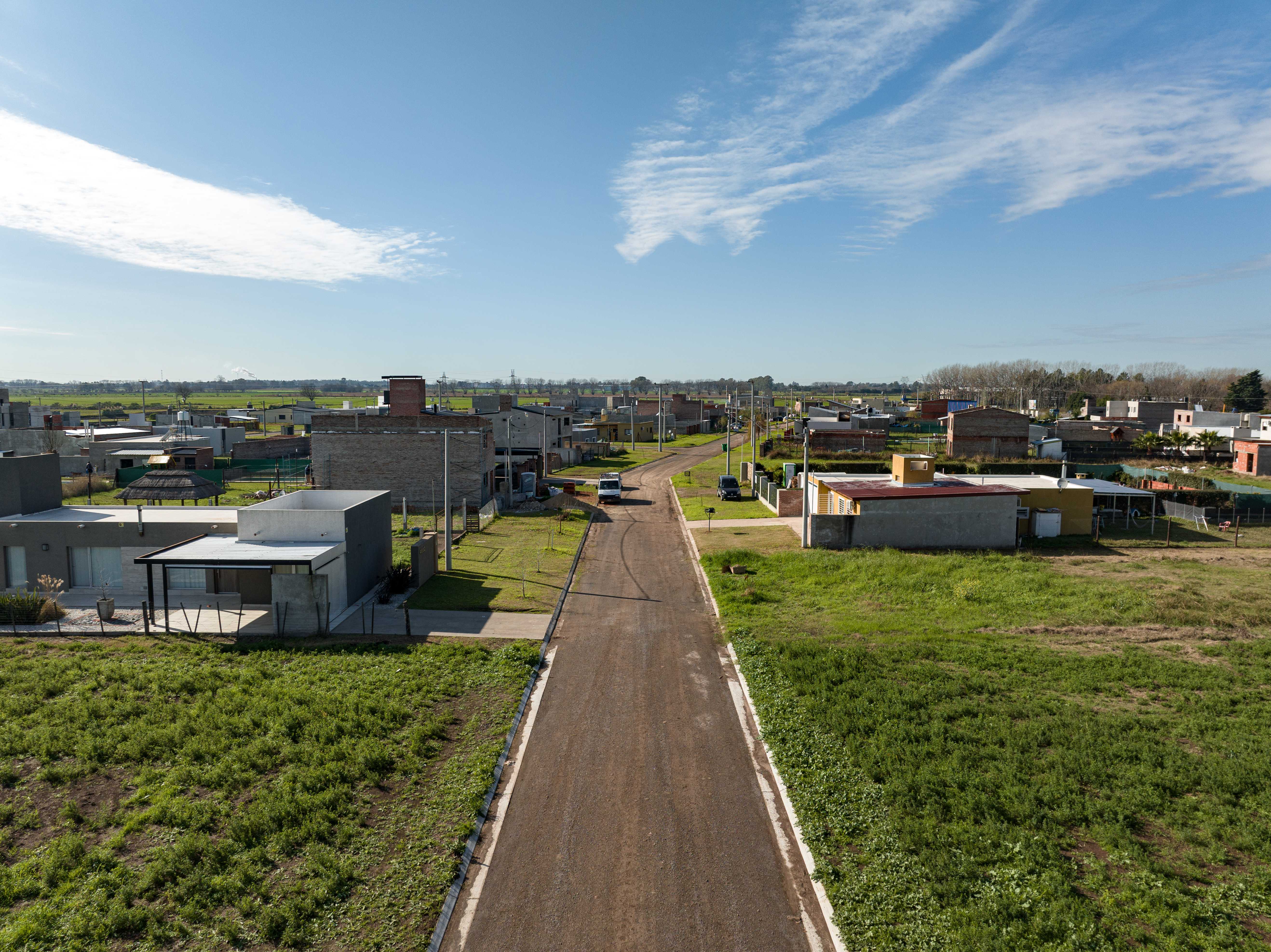 Vista aérea de una urbanización de Fantín Desarrollos con calle central y lotes arbolados